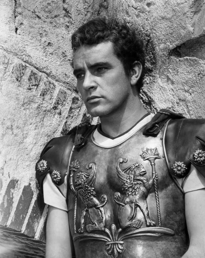 Burton incarne Marcellus Gallio, un tribun romain qui commande l’unité responsable de la crucifixion de Jésus. Ce personnage traverse un tourment intérieur intense, symbolisé par la possession de la tunique (the robe), objet lourd de sens et source de culpabilité.