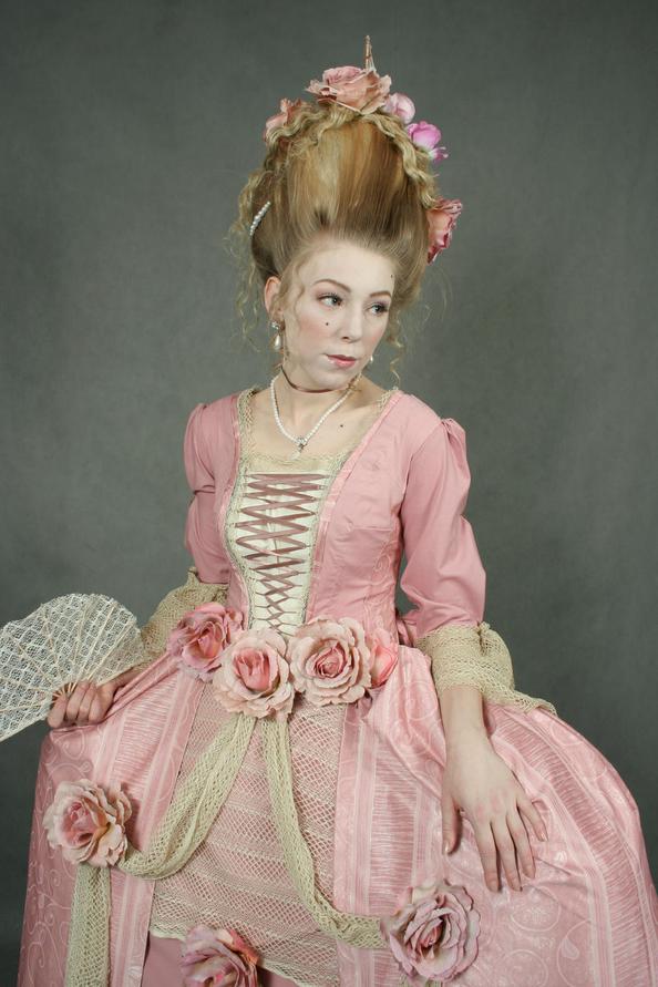 Sa signature ? Des robes pouffes aux vastes jupons à paniers, des coiffures à couper le souffle surnommées « poufs », et surtout l’introduction audacieuse de lachemise à la reine. Ce vêtement, fluide et simple, sans corset, a d'abord choqué : enfin une robe qui laisse paraître la silhouette naturelle, libérant les femmes des carcans habituels de la mode rigide. Cette pièce résume bien le paradoxe du Rococo : à la fois luxe ostentatoire et quête d’une certaine liberté dans la douceur et la simplicité.